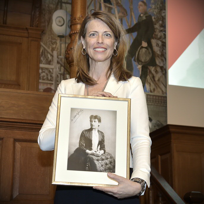 Petra Stienen met een foto van Aletta Jacobs, in 1871 de eerste vrouwelijke student aan een Nederlandse universiteit.