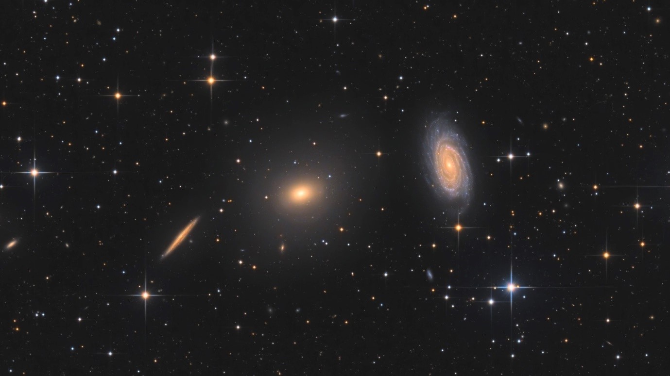 In het midden het elliptische sterrenstelsel NGC5982, rechts daarvan het spiraalvormige sterrenstelsel NGC5985. Deze twee soorten sterrenstelsels blijken zich heel verschillend te gedragen als het gaat om de extra zwaartekracht – en dus mogelijk de donkere materie – in de buitengebieden van de stelsels. Foto: Bart Delsaert (www.delsaert.com).