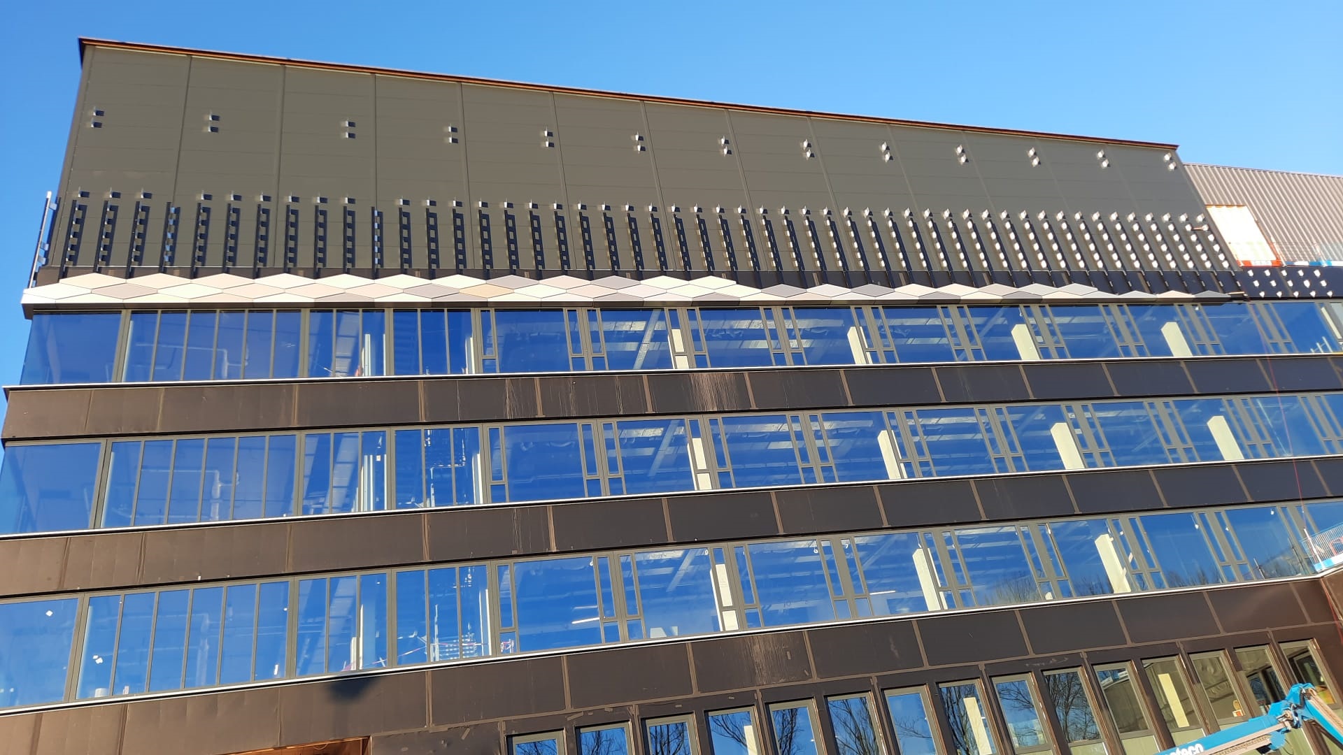 Eerste 'wybertjes' zijn aangebracht boven de hoogste ramen op de gevel van Feringa BuildingFirst 'wybert' slates have been installed above the highest windows on the façade of the Feringa Building