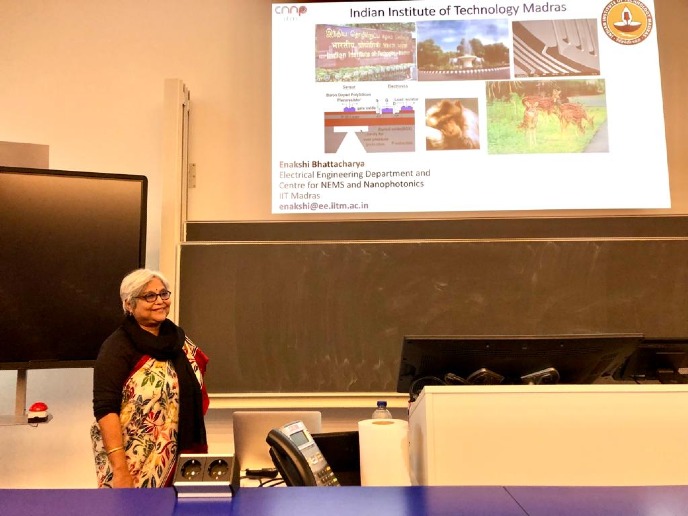 Prof. Enakshi Bhattacharya at a lecture hall in front of the screen with her presentation smiling