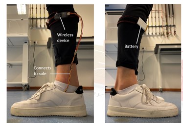 a picture of a human foot in a sneaker shoe, having wires and a battery connected to the sole