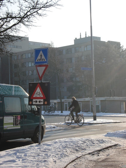 Een waarschuwingsbord met knipperlampen bij een fietspad met fietsverkeer in twee richtingen
