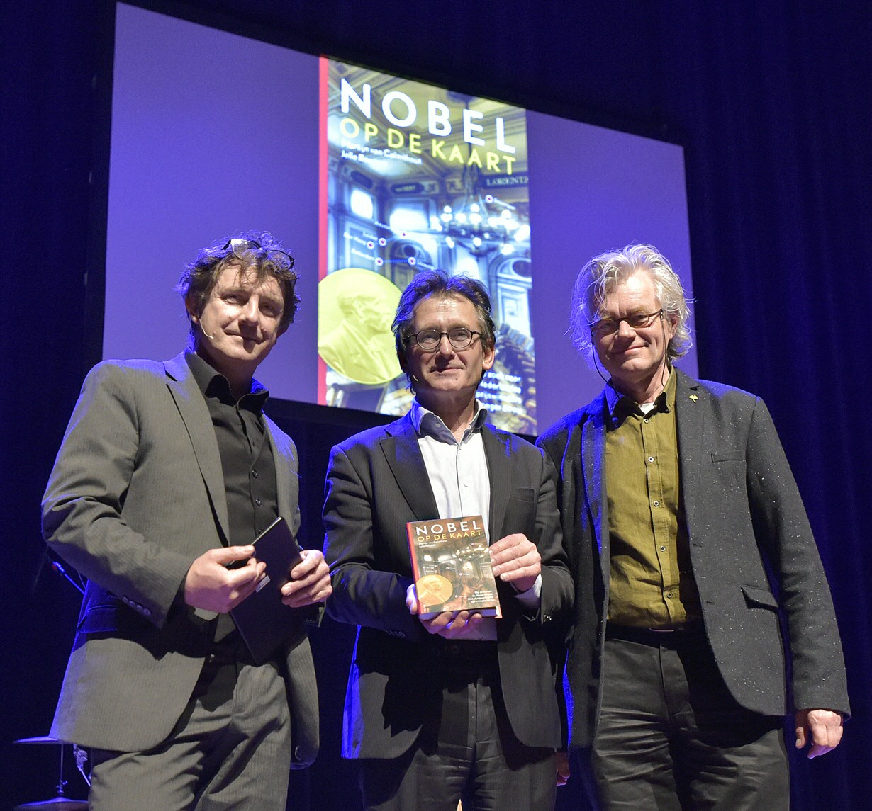 Martijn van Calmthout and Jelle Reumer present Feringa with their book 'Nobel op de kaart' [Nobel on the map]