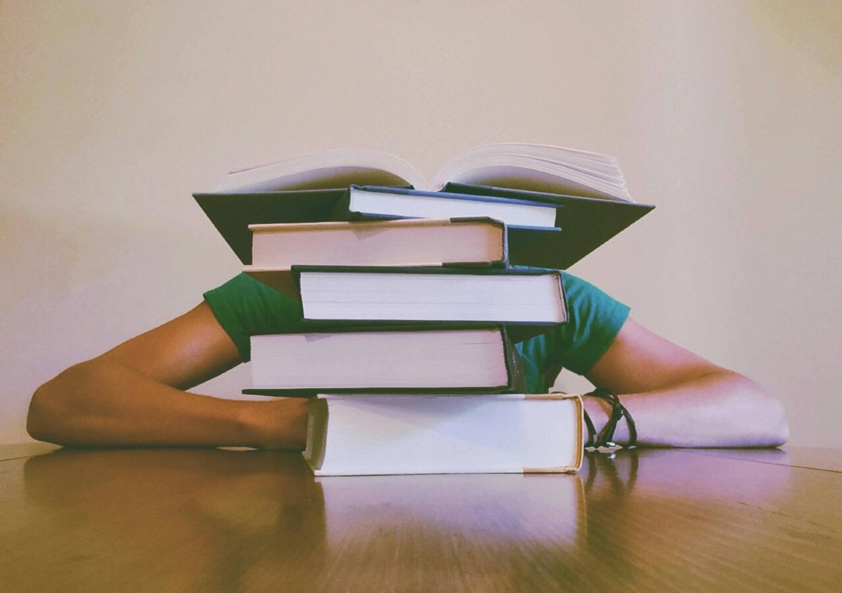 foto van student verstopt achter boeken
