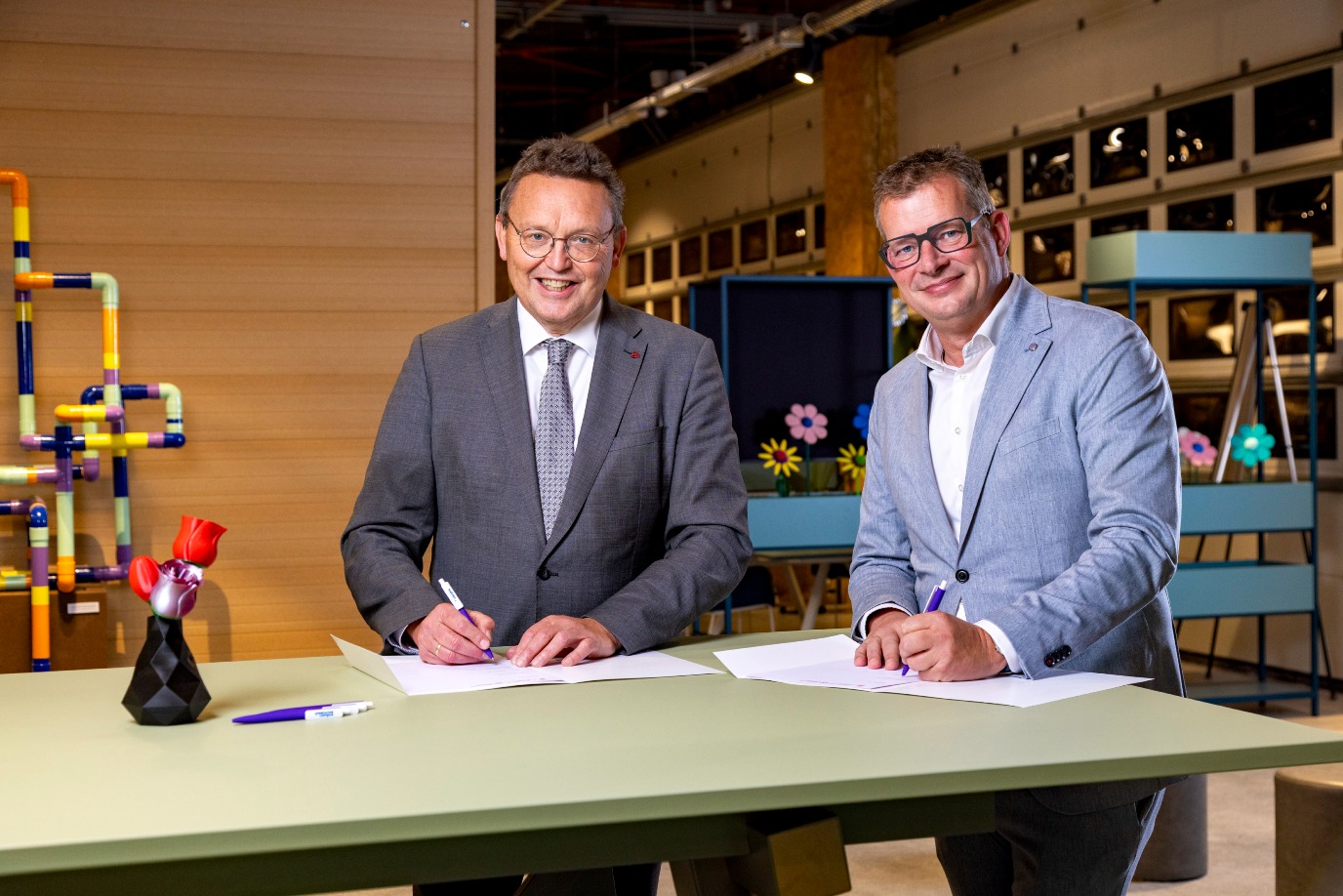 Foto: prof. dr. J. de Vries, voorzitter college van bestuur van de RijksuniversiteitGroningen en wethouder Raymond Wanders zetten een handtekening onder de overeenkomst