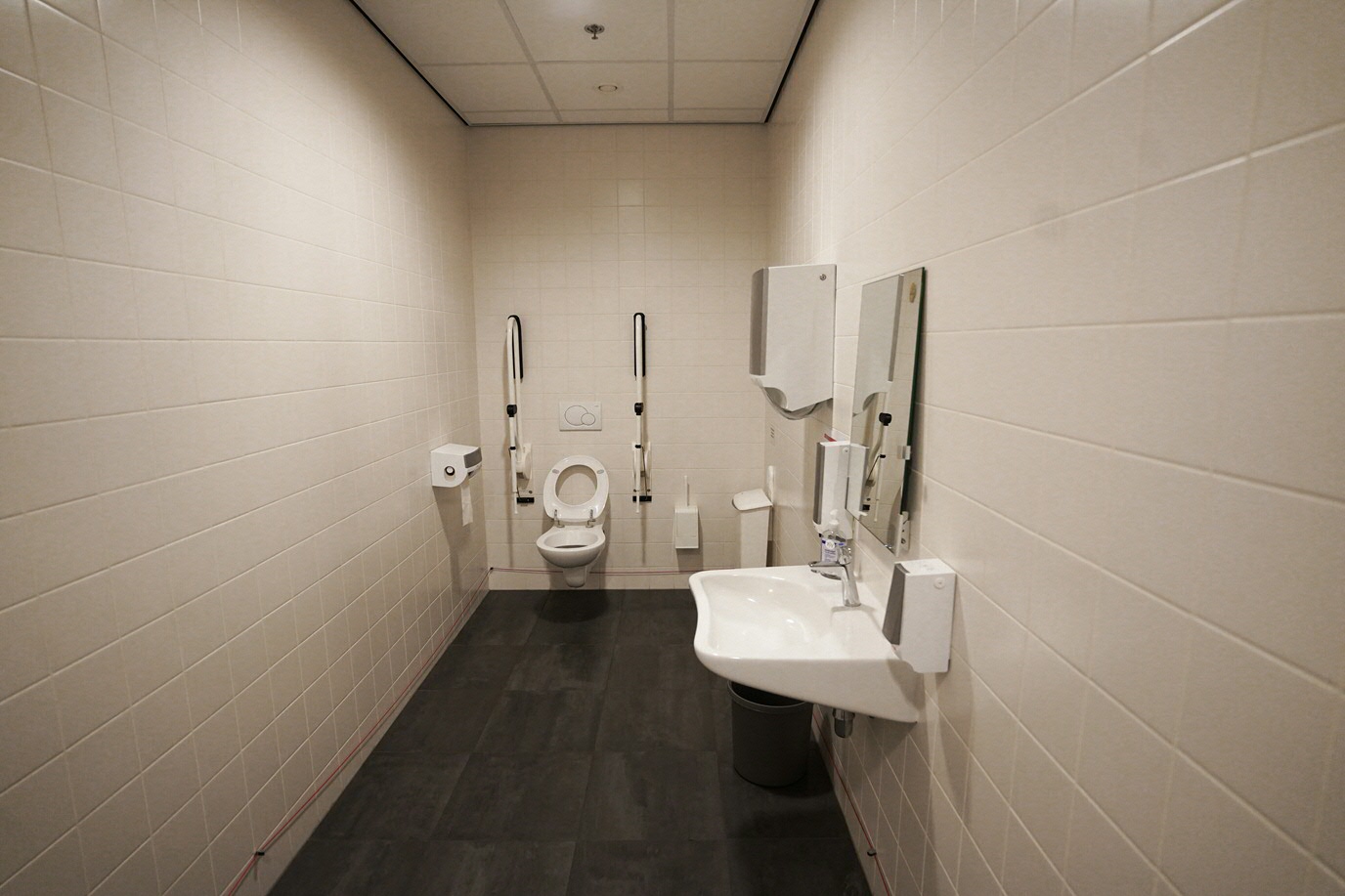Wheelchair-friendly toilet after back entrance with sliding doors immediately on right hand side