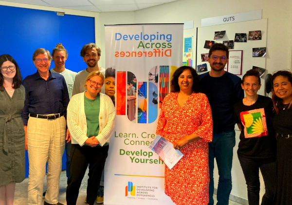 9 people standing by a sign that says "Developing Across Differences"