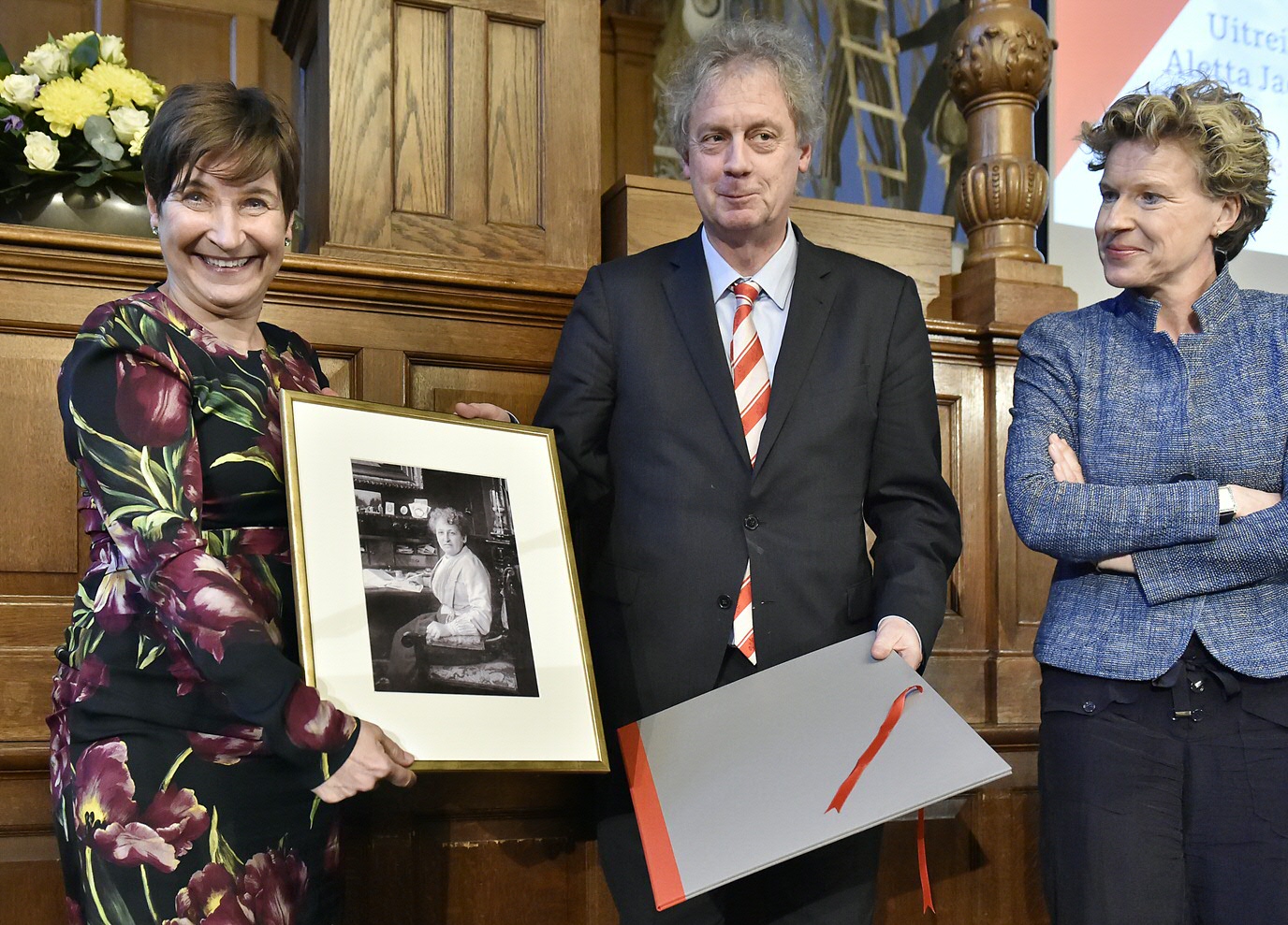 Lilianne Ploumen ontvangt foto van Aletta Jacobs van Prof. dr. Elmer Sterken (Rector Magnificus RUG) en Prof. dr. Janka Stoker (voorzitter jury Aletta Jacobs Prijs en hoogleraar Leiderschap en Organisatieverandering, Faculteit Economie en Bedrijfskunde)