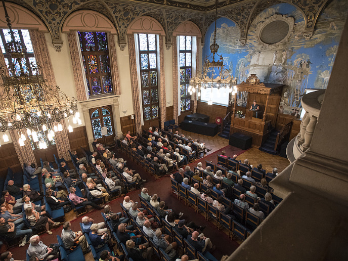 Een volle aula luistert aandachtig