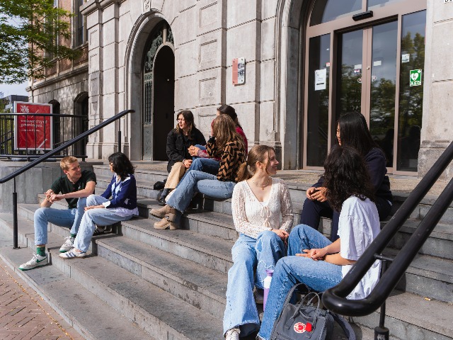 Students sitting on the outside stairs of De Beurs