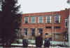 Recente foto van het gebouw Grote Appelstraat 10 dat van buiten niet is veranderd. Rechts de ingang met schuin daarboven de smalle ramen van de gebruikersponskamer. Ervoor vlnr. Hans Kelders, Hayko Wind en Herman Beekman, RC-medewekers van een jongere lichting.