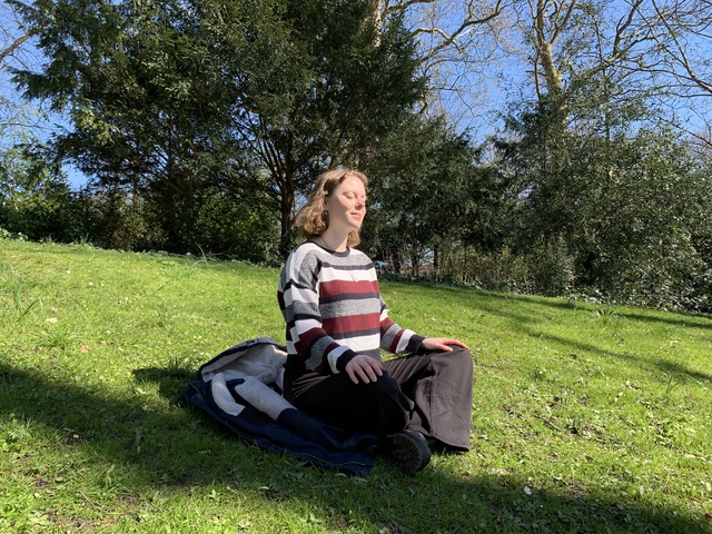 Student Hylke meditates in the park to reduce stress.