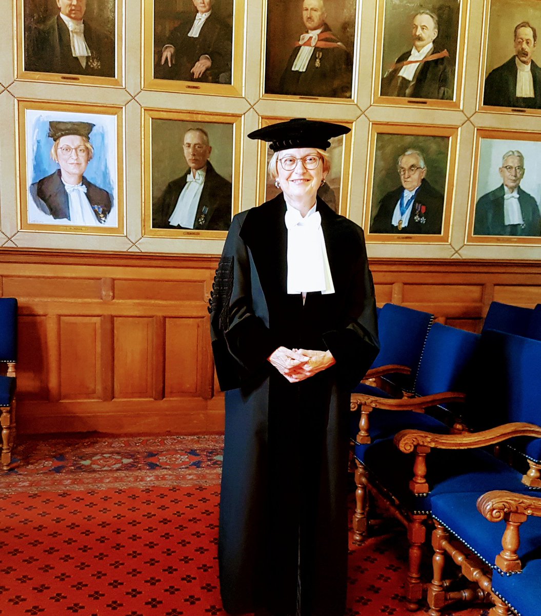 Rector Maginificus Cisca Wijmenga standing proudly next to her portrait up on the wall with all the other rectors.
