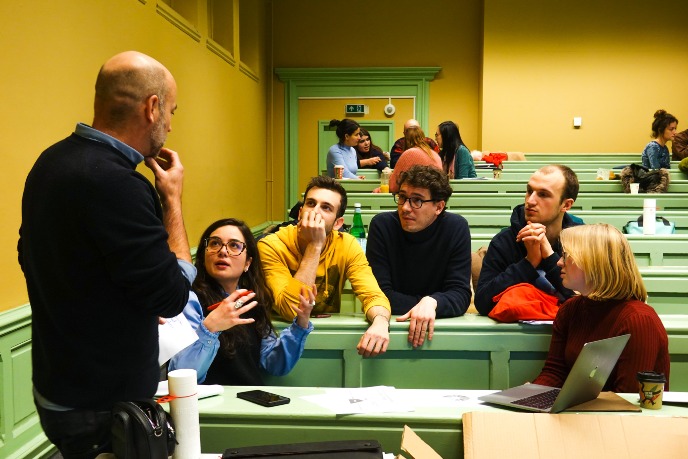 student from a group of students discussing with professor