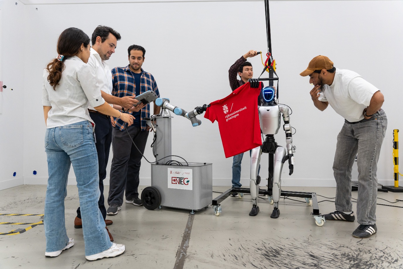 De onderzoekers testen met deze robots hoe ze het beste textiel kunnen beetpakken. Van links naar rechts: Sepide Taleb, Mauricio Mu&ntilde;oz-Arias, Ammar Akhlaq Ahmed, Azamat Kaibaldiyev, Ali Ahmadi. | Beeld Willem Sern&eacute; 