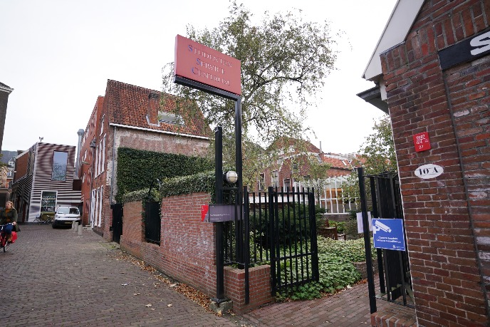 Behind the fence is the main entrance of the building