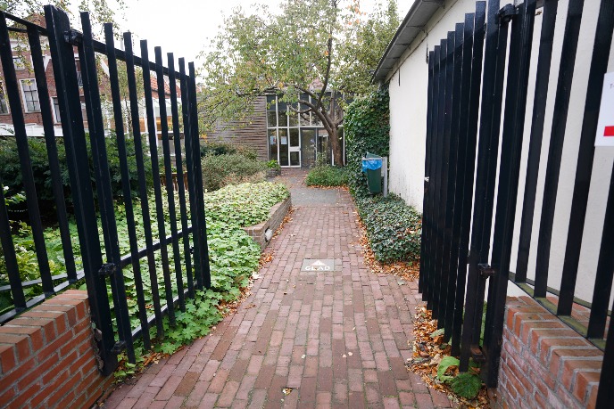 Achter het hek bevindt zich de hoofdingang van het gebouw