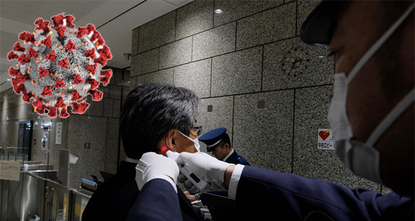 A security guard measures a visitor's temperature in a government building in Tokyo ©AFP