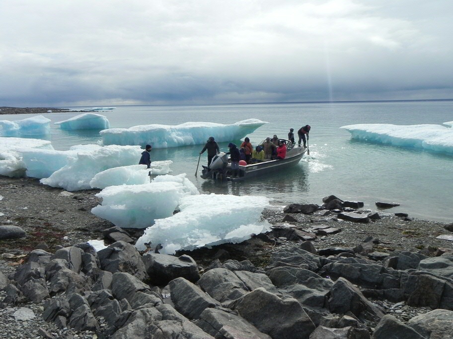 Sean Desjardins (left, on shore) welcomes Igloolik Elders to Avvajja, Nunavut, Arctic Canada, 2018. (Photo by Scott Rufolo)