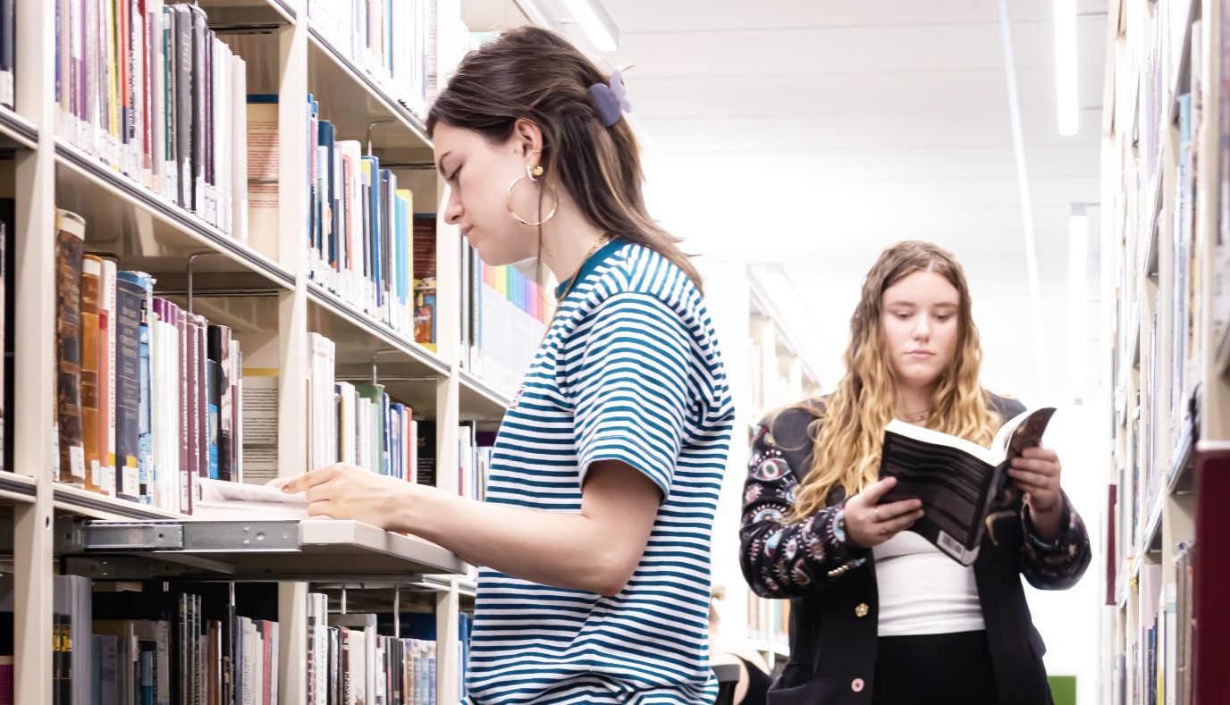 Student taking a book from the shelves in the library