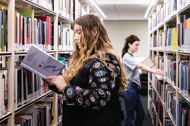Studenten bij boekenkasten op studiezaal