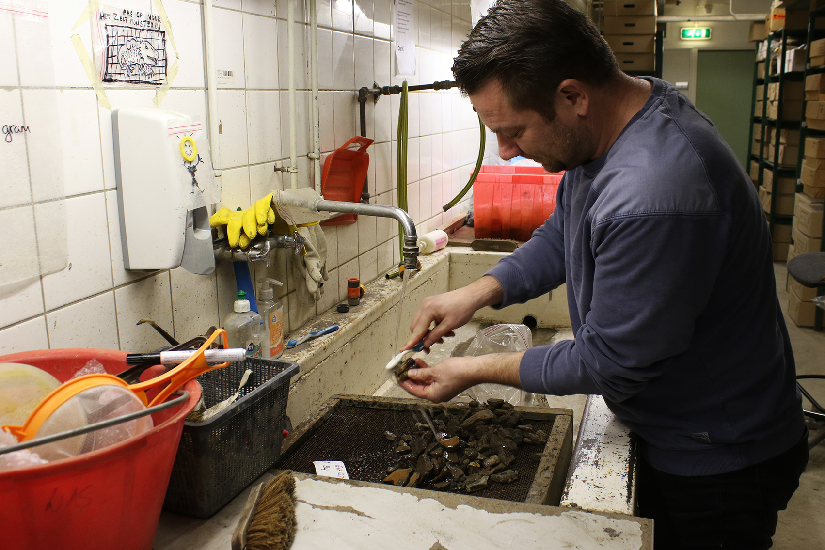 De spoelkelder. Vondsten worden hier indien nodig verder afgespoeld, gezeefd en geborsteld. Voor het fijne werk ligt de tandenborstel klaar.The rinsing cellar. Finds are further rinsed, sieved and brushed here if necessary. There is also a toothbrush for the finer details.