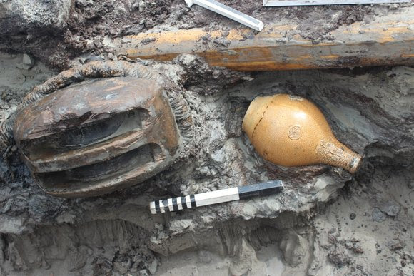 Links een tweeschijfsblok met strop van touw, rechts een intacte baardmankruik uit het Duitse RijnlandLeft a double block with rope noose, right an intact Bartmann jug from the Rhineland in Germany.