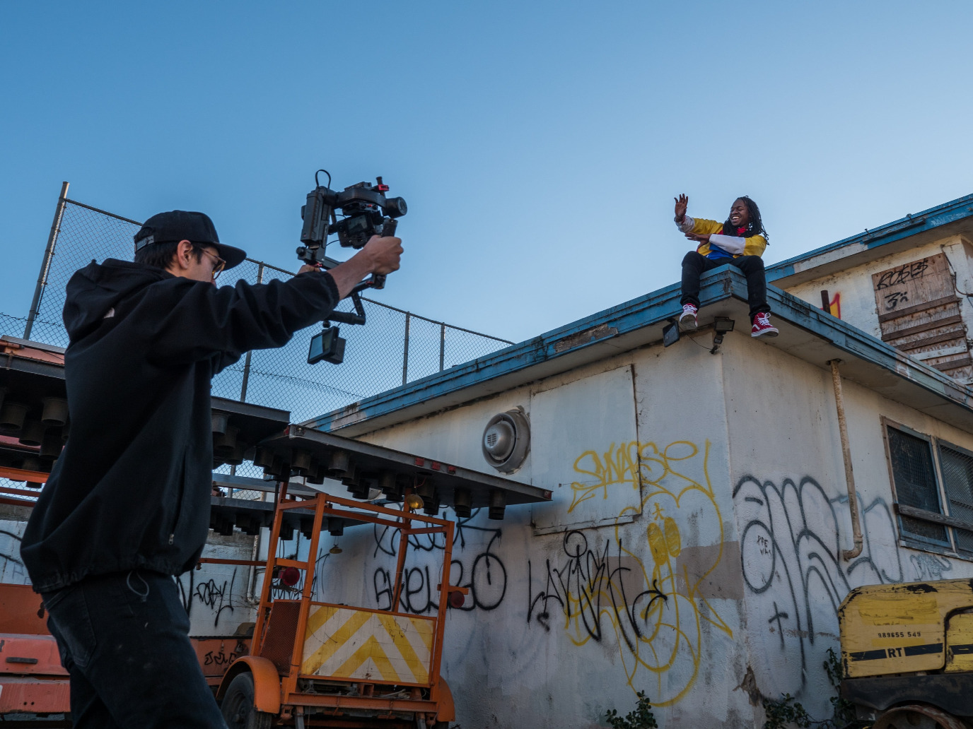 Person taking a video of a smiling person on a roof.