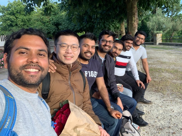 7 group members smiling sitting in a row in a park