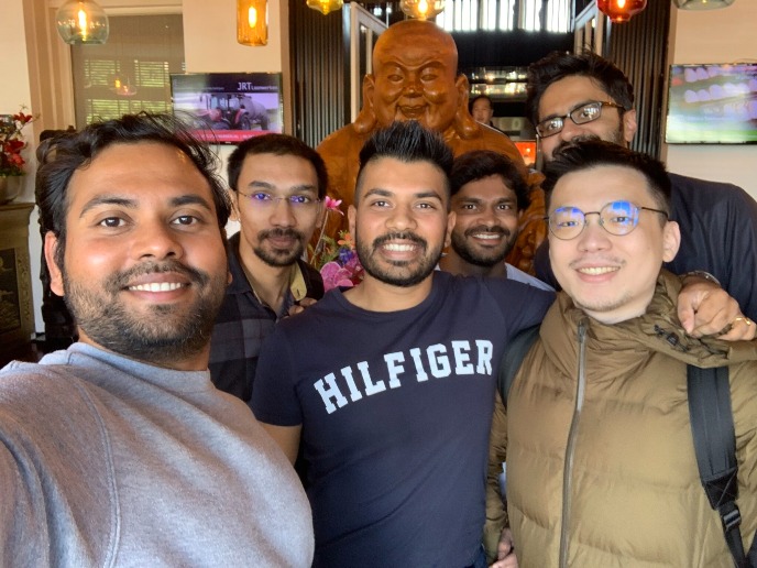 The group members are in front of a statue of the god of wealth in a restaurant