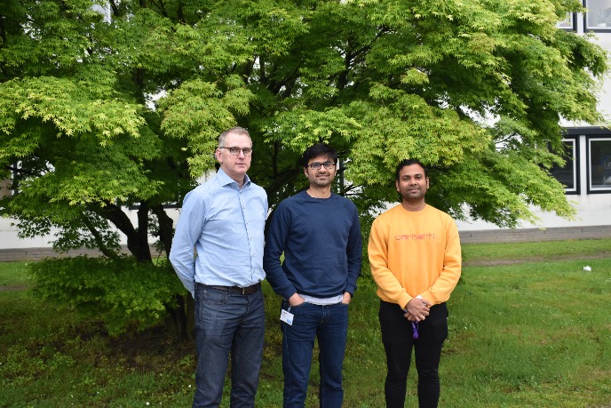 3 gentlemen in front of a green tree