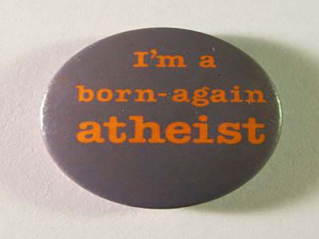 “Born-again atheist badge, c.1987” by Unknown – Personal collection. Licensed under Public Domain via Wikimedia Commons