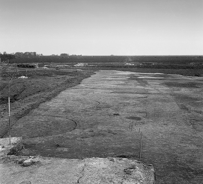 De afgraving van de kloosterterp Klaarkamp met zicht op het oosten. De ronde poeren en fundamentsleuven van de abdijkerk zijn ingekrast of omlijnd met bamboestokjes en touw zodat de medewerkers van het Biologisch Archeologisch Instituut de sporen konden intekenen.