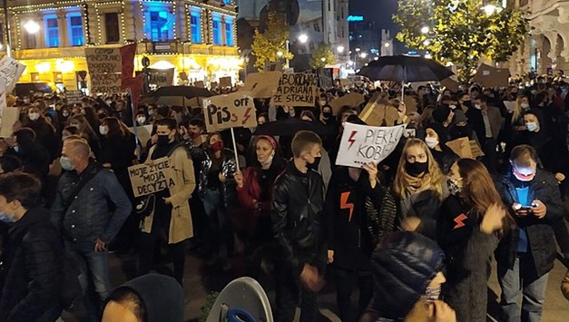 Zdjęcie z jednego z protestów Ogólnopolskiego Strajku Kobiet. Na ulicy stoją liczni protestujący, w maskach, z symbolami czerwonych błyskawic i z transparentami, na których widnieją napisy, m.in.: "Moje życie, moja decyzja", "PiS off" i "Piekło kobiet".