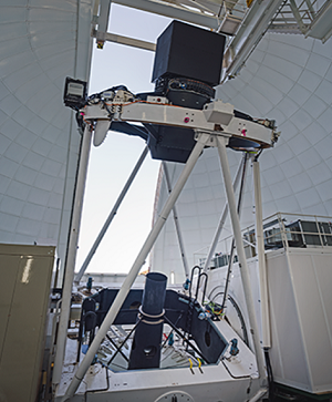 De William Herschel Telescoop met WEAVE. De WEAVE-positioner is ondergebracht in de 1,8 meter hoge zwarte doos boven de bovenste ring. Optische vezels lopen langs de telescoopstructuur naar de lichtgrijze behuizing links, waar de WEAVE-spectrograaf is ondergebracht. Credit: Sebastian Kramer.