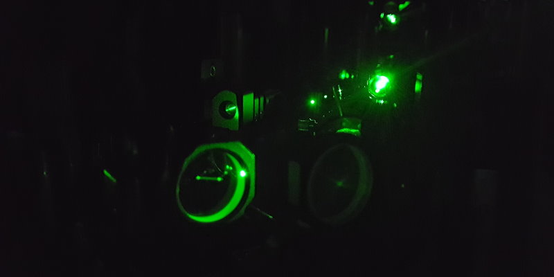 A green laser beam is passing various optical elements in our home-built fluorescence experiment.