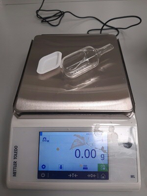 Two ways of weighing; on the left a paper disposable weiging dish, on the right a washable glass weighing instrument (more sustainable)