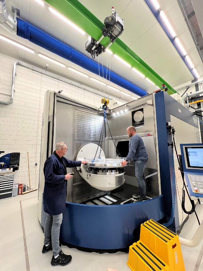 Operator Menno Schuil plaatst, samen met een collega, een blok aluminium in de freesmachine Together with a colleague, operator Menno Schuil places an aluminium block in the milling machine 