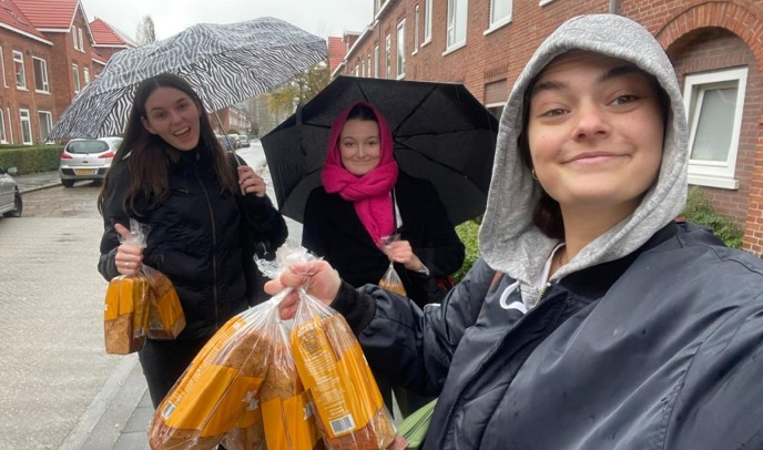 Studenten met een Knols Koek als presentje voor buurtbewoners