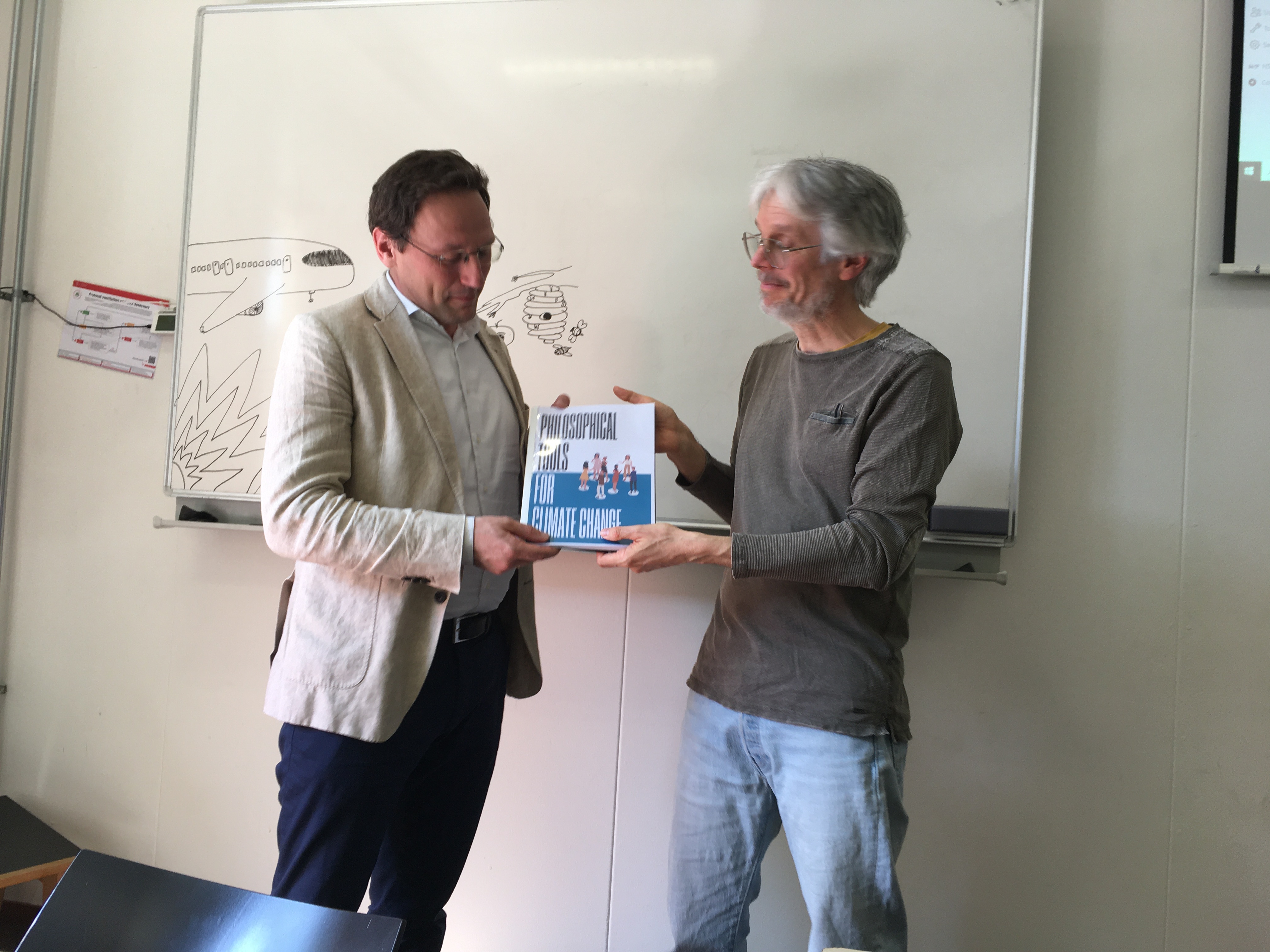 Marc Pauly (r) overhandigt het papieren boek aan Lorenzo Squintani